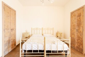 A bedroom with a metal bed frame, two bedside tables, a wooden wardrobe, and a wooden floor.