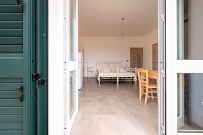 Ein Schlafzimmer mit Bett, Nachttisch und Stuhl, einem Fenster und einer Tür.