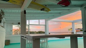A room with a view of the sunset, a table, chairs, and a ceiling fan. - Cozy Beachfront House in Chiclana de la Frontera (Chiclana de la Frontera)