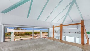 A bedroom with a large bed, a wooden ceiling, and a view of the outside. - Cozy Beachfront House in Chiclana de la Frontera (Chiclana de la Frontera)