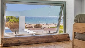 A view through a window of a beachside property with a wooden floor, a white wall, and a clear blue sky. - Cozy Beachfront House in Chiclana de la Frontera (Chiclana de la Frontera)