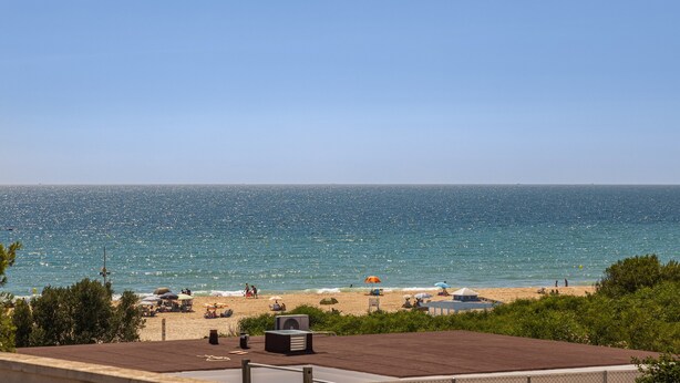 A beach view with umbrellas, a pool, and a clear sky. - Cozy Beachfront House in Chiclana de la Frontera (Chiclana de la Frontera)
