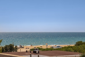 A beach view with umbrellas, a pool, and a clear sky.