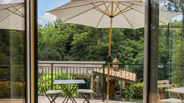 A glass door leading to an outdoor patio with a table, chairs, and a large umbrella. - Holiday Home 'Cascina Oddone Prati Winery' with Shared Pool, Wi-Fi and Air Conditioning (Strevi)