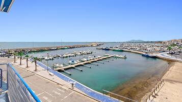 Un port de plaisance avec des bateaux amarrés, un ciel dégagé et une montagne qui se profile à l’horizon.