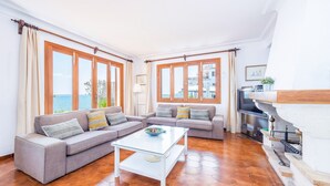 A living room with two sofas, a glass coffee table, a fireplace, and large windows with a view. - Villa 'Ca'n Torrens' with Sea Views, Wi-Fi and Air Conditioning (Alcúdia)