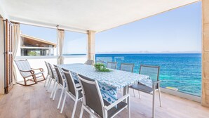 A balcony with a table and chairs, a view of the sea, and a building in the background. - Villa 'Ca'n Torrens' with Sea Views, Wi-Fi and Air Conditioning (Alcúdia)
