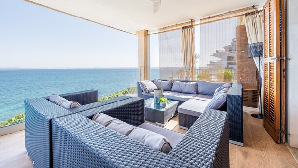 A balcony with wicker furniture, a ceiling fan, and a view of the sea. - Villa 'Ca'n Torrens' with Sea Views, Wi-Fi and Air Conditioning (Alcúdia)