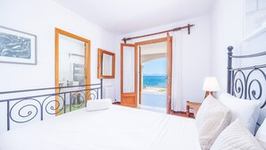 A bedroom with a bed, a view of the sea, a bathroom with a towel rack, and a painting on the wall. - Villa 'Ca'n Torrens' with Sea Views, Wi-Fi and Air Conditioning (Alcúdia)
