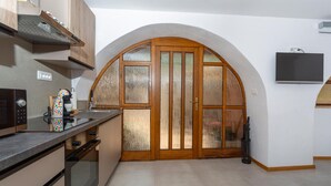 A kitchen with a microwave, coffee maker, and a large arched doorway.