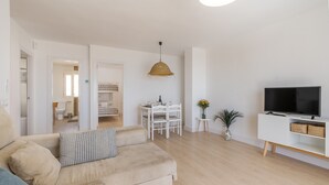 Een moderne woonkamer met een bank, televisie en eethoek.