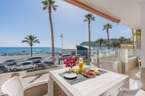 A balcony with a table set for breakfast, overlooking a beach with parked cars and palm trees. - Apartment 'Primera Linea De Playa La Herradura' with Sea Views, Balcony and Wi-Fi (Almuñécar)