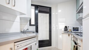 A modern kitchen with white cabinets, a dishwasher, a microwave, and a coffee maker. - Apartment 'Valencia Playa' with Sea View, Wi-Fi and Air Conditioning (Alboraya)