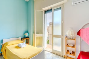 Una habitación con una cama, un globo en una mesita auxiliar, una toalla roja y un balcón con vistas.