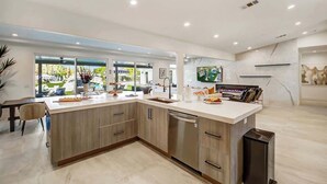 A modern kitchen with a large island, stainless steel appliances, and a view of the outdoors.