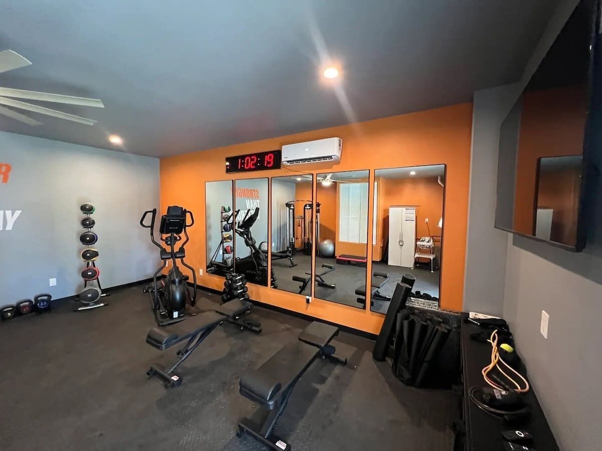 A gym with exercise equipment, a digital clock, and a mirror.