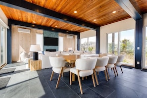 Un comedor moderno con techo de madera, una gran mesa redonda y varias sillas.