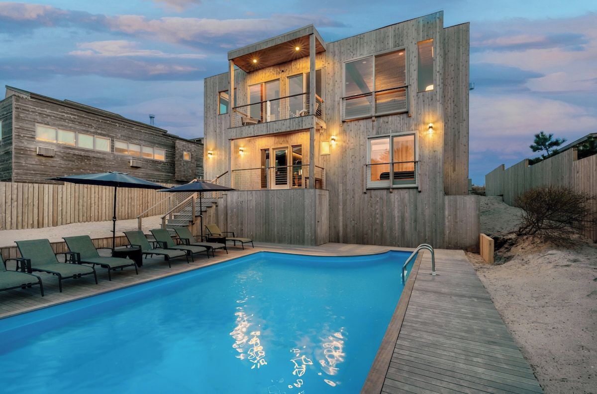 Ein modernes, zweistöckiges Gebäude mit Schwimmbad, Außenbereich und einer Holzterrasse.