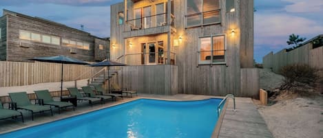 Ein modernes, zweistöckiges Gebäude mit Schwimmbad, Außenbereich und einer Holzterrasse.