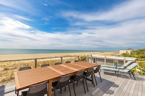 Una terraza de madera con una mesa y sillas que da a una playa.