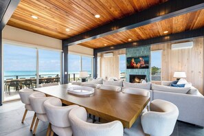 A spacious living area with a large wooden table, comfortable seating, a fireplace, and a television.