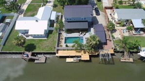 Vue aérienne d’une propriété résidentielle dotée d’une piscine, d’un quai et de maisons voisines.