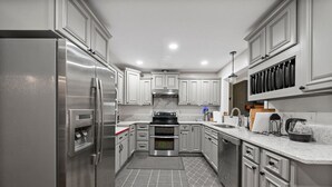 Une cuisine moderne dotée d’appareils électroménagers en acier inoxydable, de meubles de rangement gris et d’un dosseret en marbre.
