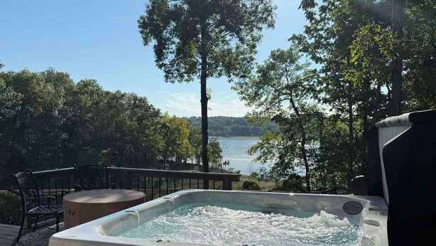 Un bain à remous sur une terrasse, avec vue sur un lac et des arbres.