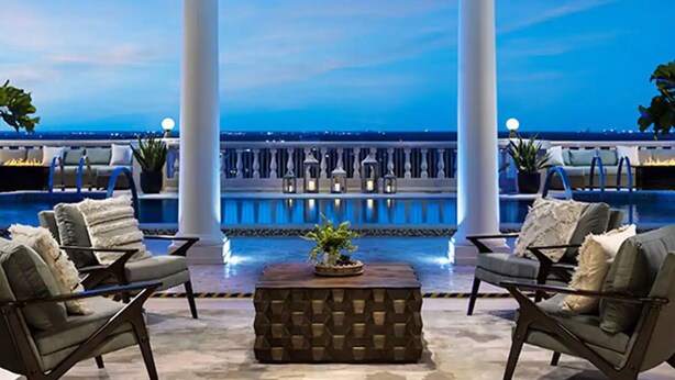 A poolside area with two lounge chairs, a textured coffee table, and a view of the ocean. - “The Disney Diamond Bungalow” (Kissimmee)
