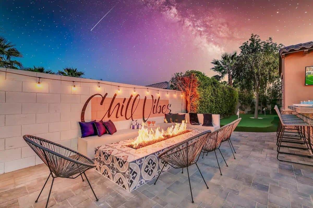 An outdoor patio with a fire feature, seating, and a wall with 'Chill Vibes' text.