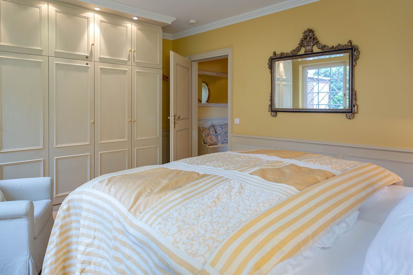 A bedroom with a large bed, a wardrobe, and a mirror on the wall.