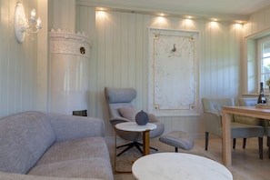 Una habitación con un sofá, una silla, una mesa redonda y un adorno en la pared.