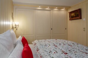 Une chambre à coucher comprenant un lit, une table de chevet, une lampe fixée au mur et une armoire.