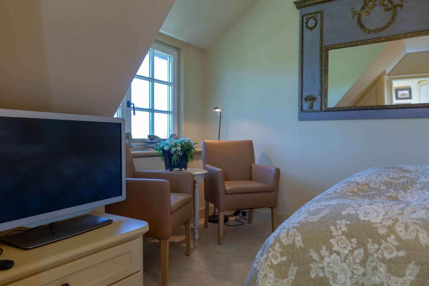 Une chambre à coucher comprenant un lit, une télévision, un bureau avec une chaise, une fenêtre et un miroir.