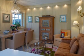 Un salon chaleureux avec un meuble en bois, une table à manger, des chaises, un canapé et un lustre.