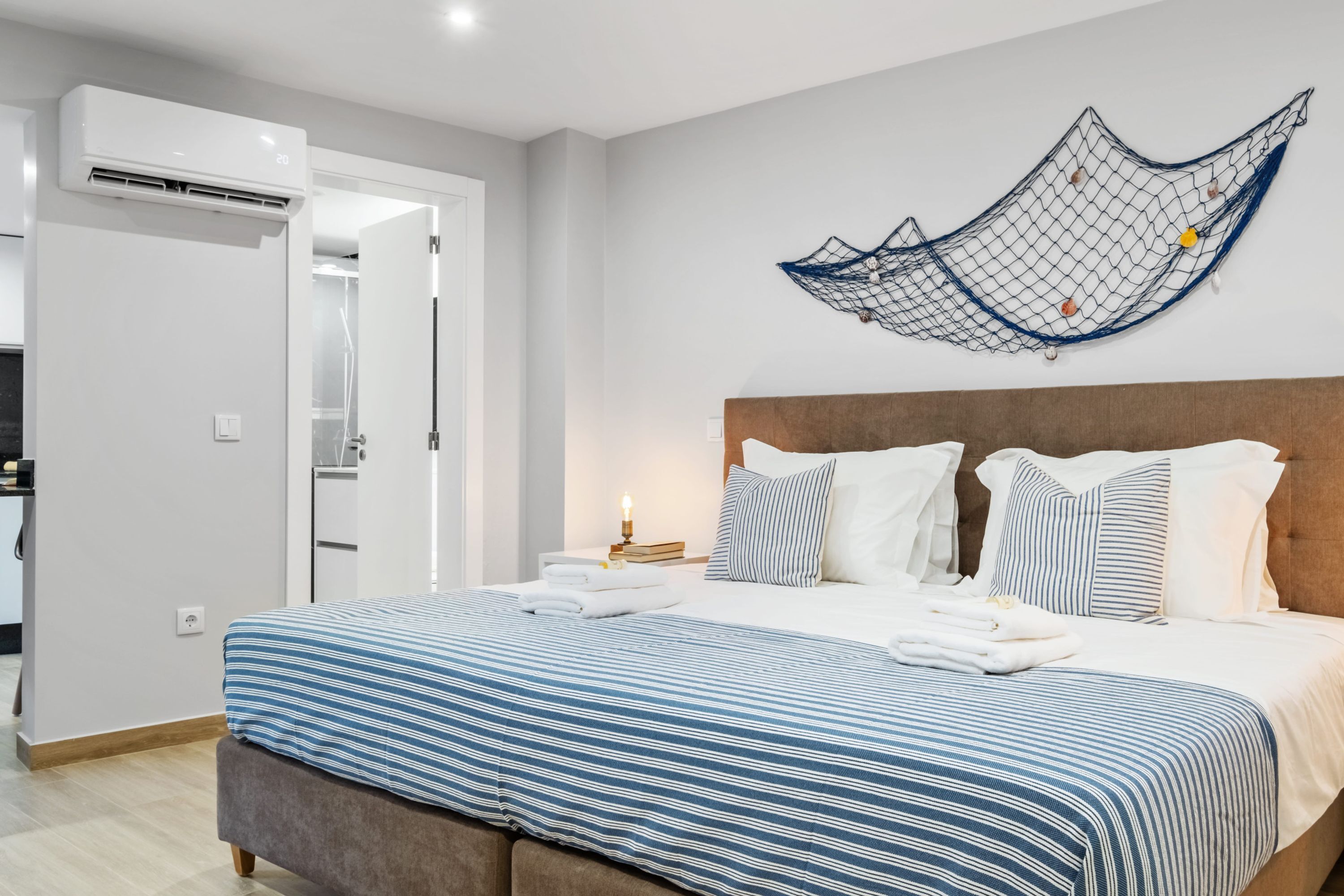 A modern hotel room with a large bed, a wooden headboard, and a wall-mounted hammock.