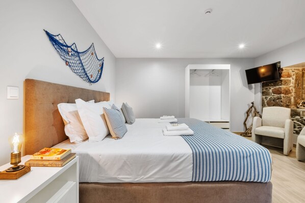 A modern bedroom with a large bed, a TV, a stone wall, and a hanging net.