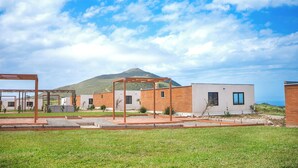 A modern building with a flat roof, surrounded by a well-maintained lawn and a wooden pergola structure. - Single Cabin #5 - Oak Point (Ensenada)
