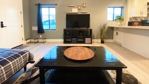 A compact living space with a dining table, a television, and a kitchenette.