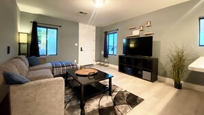 A modern living room with a sofa, coffee table, TV, and a potted plant.