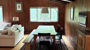 Una stanza accogliente con un tavolo in legno, un divano e una finestra vista alberi.