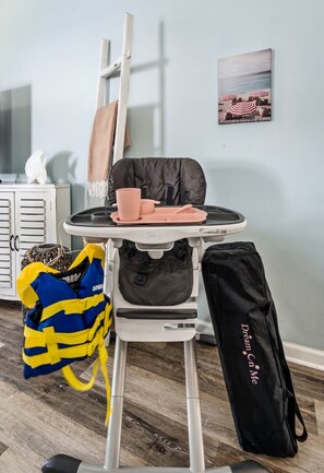 A room with a high chair, a backpack, and a bag with 'Dream On Me' text.