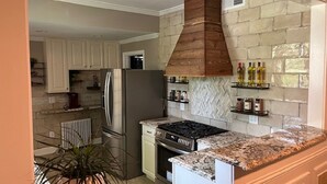 Une cuisine équipée d’une cuisinière intégrée, d’un réfrigérateur et d’un four à micro-ondes. On y trouve une plante en pot et un plan de travail avec un pare-éclaboussures.