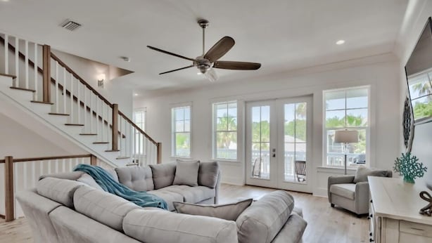 A spacious living room with a large sectional sofa, a ceiling fan, and a staircase leading to another level. - Sun Justice- 4 bd/4.5ba close to beach (Miramar Beach)