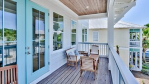 A covered porch with wooden flooring, a white railing, and a seating area with a table and chairs. - Sun Justice- 4 bd/4.5ba close to beach (Miramar Beach)