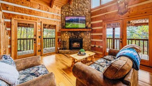 A cozy cabin interior with a stone fireplace, wooden walls, and a mounted television. - Stairway to Heaven •Breathtaking Mountain Views• (Sevierville)