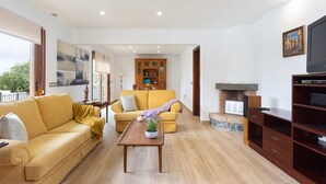 Un salón espacioso con un sofá amarillo, una mesa de centro de madera y una chimenea.