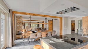 Una cocina moderna con una isla central, electrodomésticos integrados y un comedor con una pared de acento de piedra.