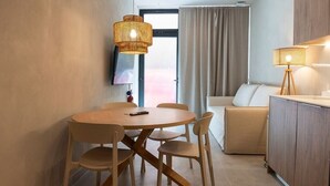 Um espaço de convívio moderno e compacto, com área de refeições, sofá e cozinha compacta.