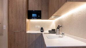 A modern kitchen with wooden cabinets, a built-in microwave, a coffee machine, and a sink with a faucet. - VLC HOST - Palau A (Valencia)